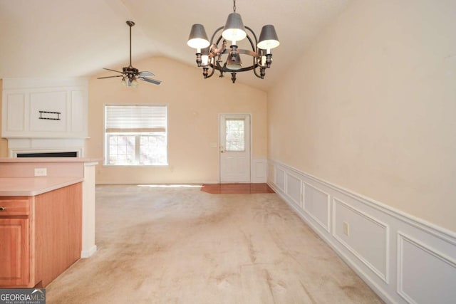 unfurnished dining area with light carpet, a decorative wall, lofted ceiling, and a healthy amount of sunlight