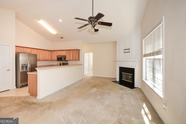 kitchen featuring a ceiling fan, light colored carpet, appliances with stainless steel finishes, light countertops, and a fireplace