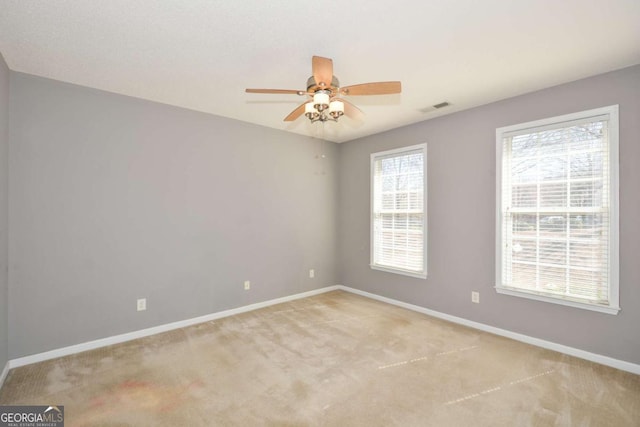 carpeted empty room featuring ceiling fan, visible vents, and baseboards