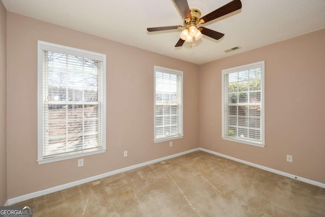 empty room featuring light carpet, ceiling fan, visible vents, and baseboards