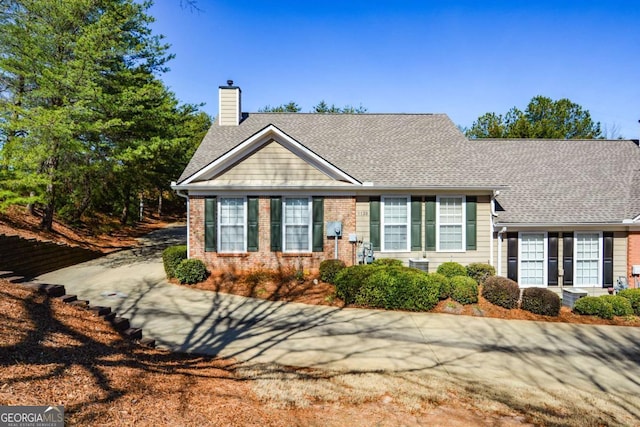 view of front of home with a shingled roof, a chimney, and brick siding