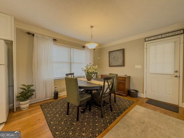 dining area with crown molding, light wood-style flooring, and baseboards