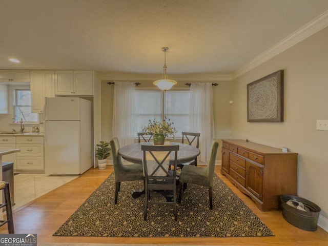 dining space featuring crown molding, light wood-style flooring, and baseboards