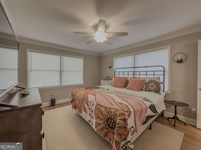 bedroom with light wood finished floors, ornamental molding, a ceiling fan, and baseboards