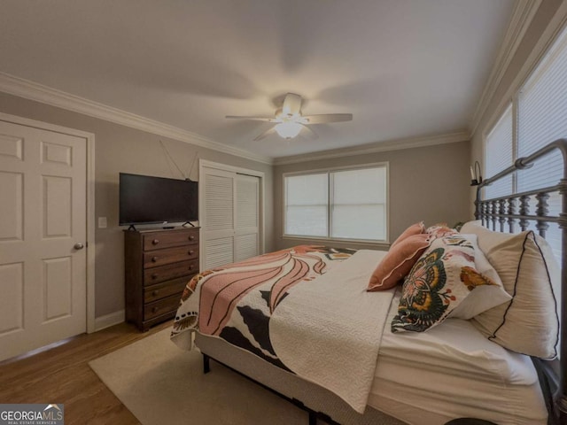 bedroom featuring a ceiling fan, a closet, crown molding, and wood finished floors