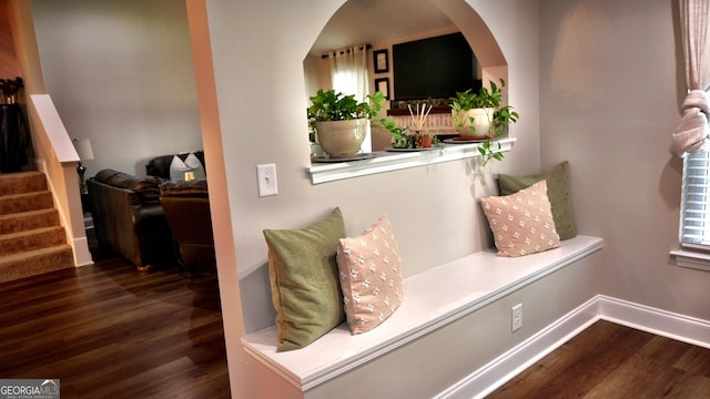 interior space with baseboards, stairway, arched walkways, and wood finished floors