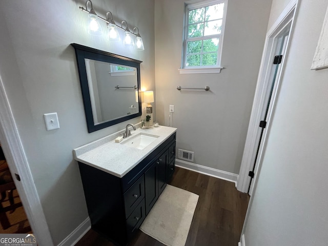 bathroom featuring baseboards, visible vents, wood finished floors, and vanity