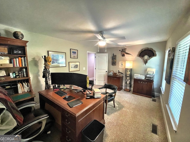 office with baseboards, visible vents, a ceiling fan, and light colored carpet