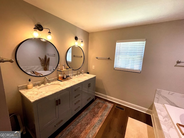 bathroom with wood finished floors, a sink, visible vents, and baseboards