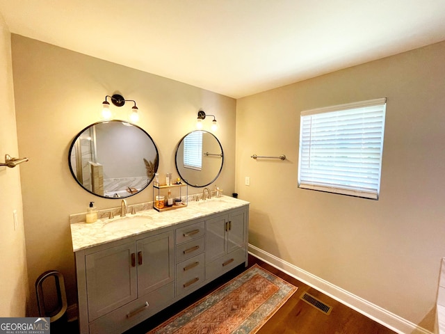 bathroom featuring double vanity, a sink, visible vents, and baseboards