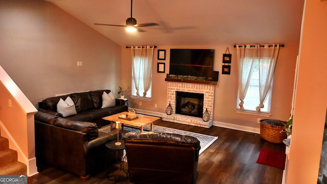 living area with a ceiling fan, lofted ceiling, dark wood-style floors, stairway, and a brick fireplace