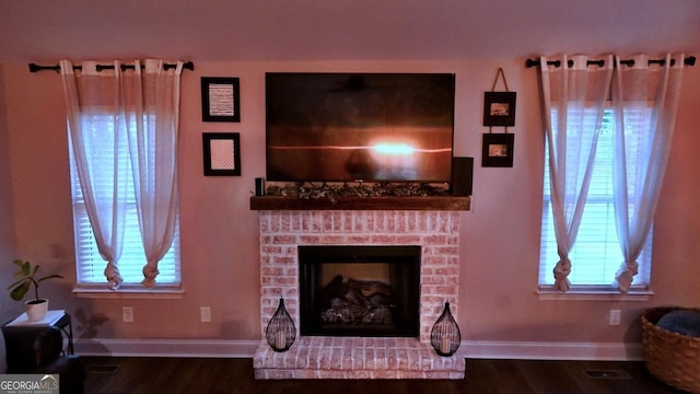 living room featuring a brick fireplace, wood finished floors, and baseboards