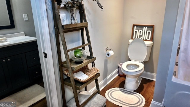 bathroom featuring baseboards, vanity, toilet, and wood finished floors