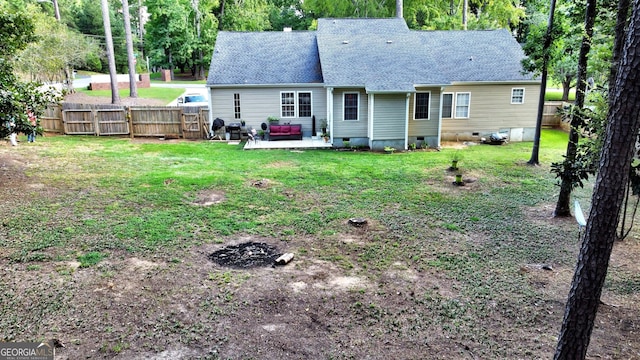 rear view of house featuring a patio, a shingled roof, fence, crawl space, and a lawn