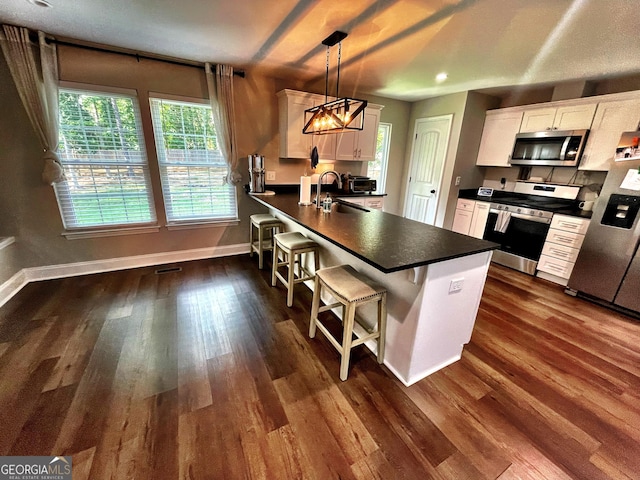 kitchen with stainless steel appliances, dark countertops, white cabinets, and a sink