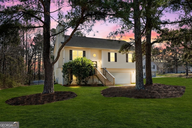 bi-level home with a front lawn, a chimney, and an attached garage