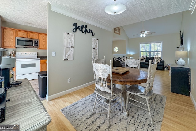 dining room featuring baseboards, lofted ceiling, ceiling fan, a textured ceiling, and light wood-type flooring