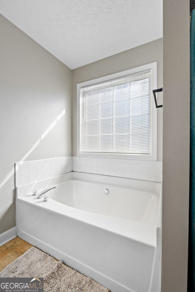 bathroom with a textured ceiling, a bath, and tile patterned floors