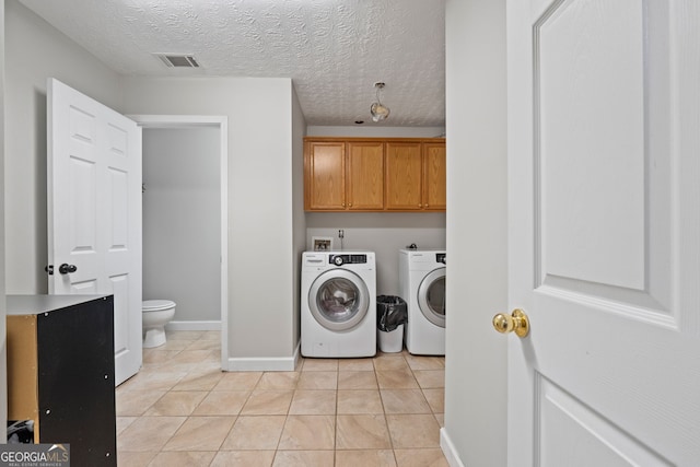 laundry room with washer and clothes dryer, light tile patterned floors, visible vents, cabinet space, and a textured ceiling