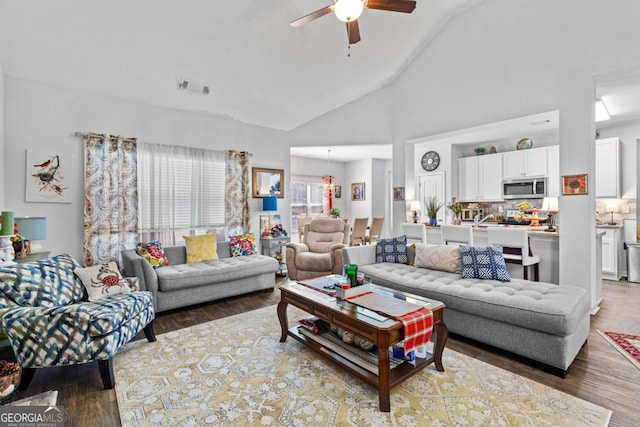 living room featuring high vaulted ceiling, a ceiling fan, visible vents, and wood finished floors