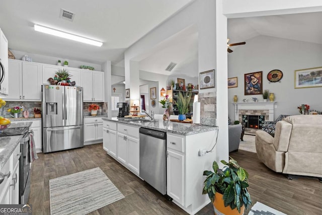 kitchen featuring a stone fireplace, stainless steel appliances, a sink, visible vents, and open floor plan