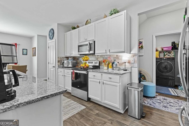 kitchen with light stone counters, dark wood-type flooring, white cabinetry, appliances with stainless steel finishes, and decorative backsplash