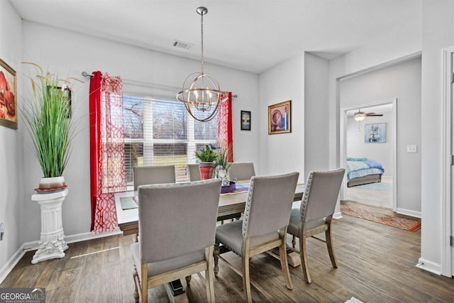 dining area featuring an inviting chandelier, baseboards, visible vents, and wood finished floors