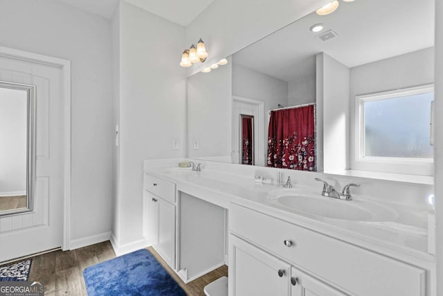 full bath featuring double vanity, visible vents, a sink, and wood finished floors