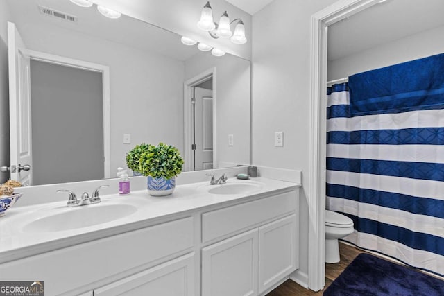 bathroom featuring double vanity, visible vents, a sink, and wood finished floors