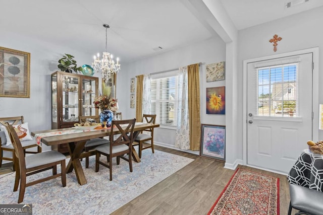 dining space with a chandelier, a wealth of natural light, light wood-style flooring, and baseboards