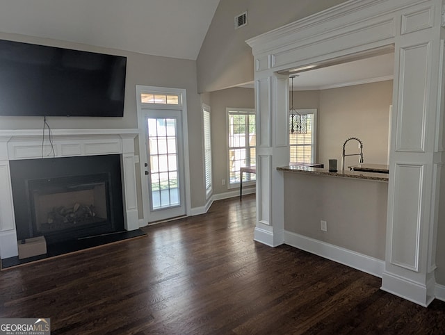 unfurnished living room featuring a glass covered fireplace, visible vents, dark wood finished floors, and lofted ceiling