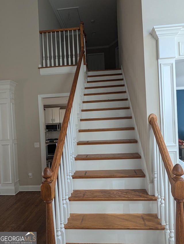 stairs with a towering ceiling, baseboards, and wood finished floors