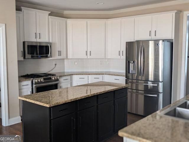 kitchen with tasteful backsplash, stainless steel appliances, dark cabinetry, and white cabinets