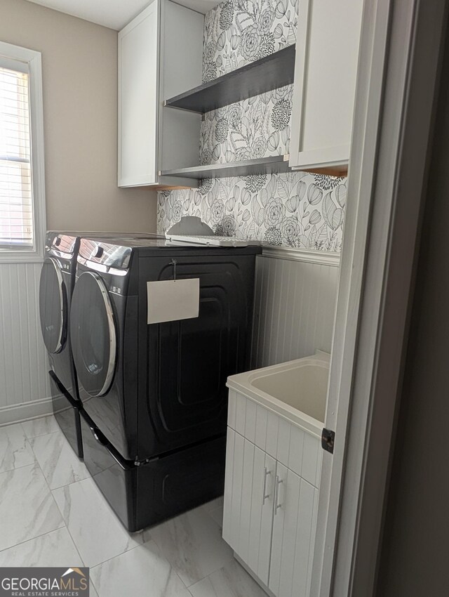 laundry room with a wainscoted wall, marble finish floor, washer and clothes dryer, and cabinet space