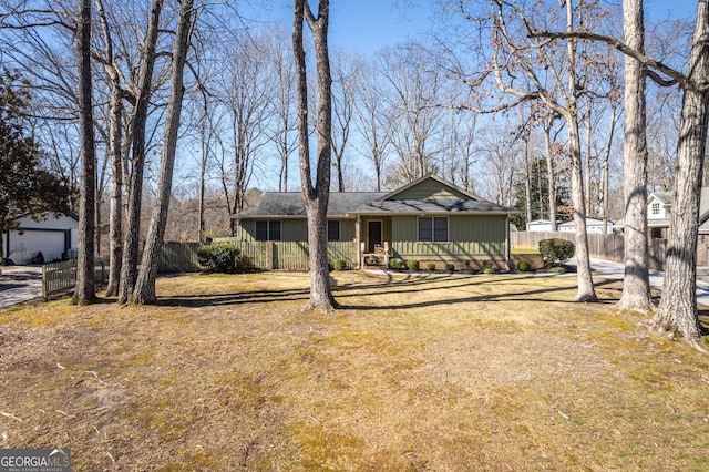 ranch-style house with a front yard, fence, and an outdoor structure