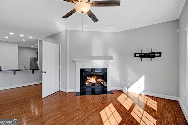 unfurnished living room with a high end fireplace, crown molding, baseboards, and wood finished floors