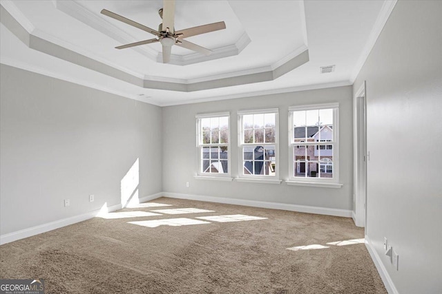 carpeted empty room with baseboards, a raised ceiling, and crown molding