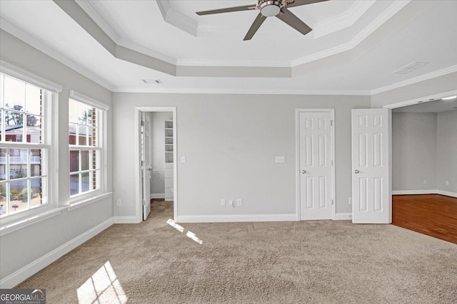 unfurnished bedroom with baseboards, a tray ceiling, carpet flooring, and ornamental molding