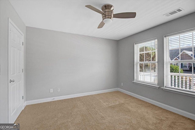 spare room with a ceiling fan, baseboards, visible vents, and carpet flooring