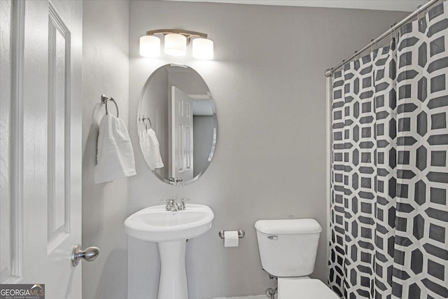 bathroom with toilet, a sink, and a shower with shower curtain