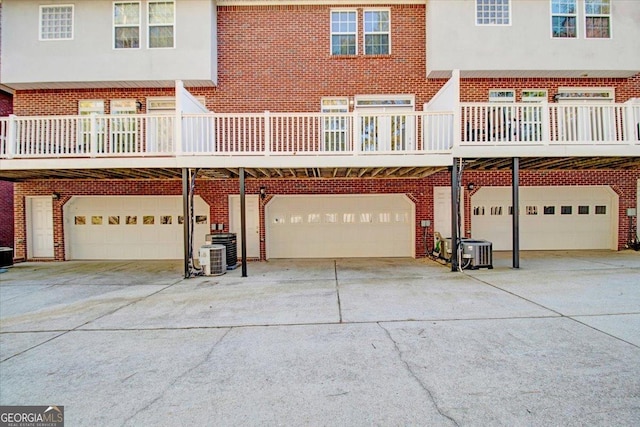 view of front of home with a garage, brick siding, and central air condition unit