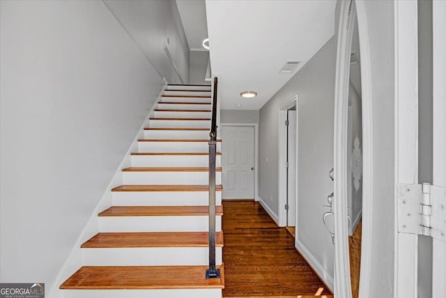 staircase featuring baseboards, visible vents, and wood finished floors