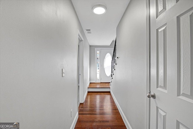 corridor featuring baseboards, visible vents, and dark wood-style flooring