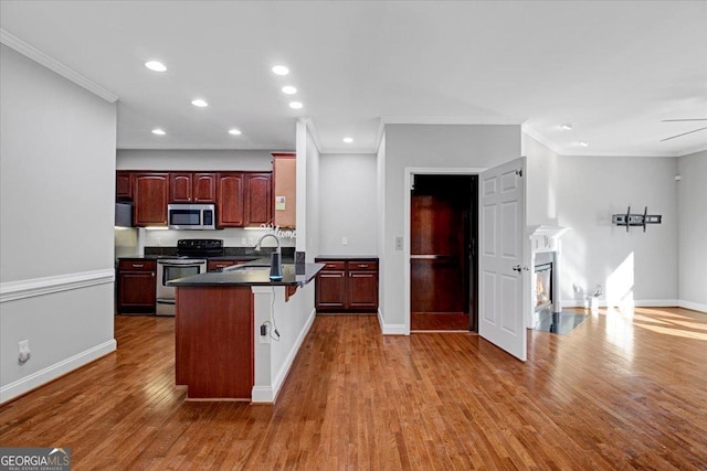 kitchen with a breakfast bar, dark countertops, appliances with stainless steel finishes, a sink, and wood finished floors