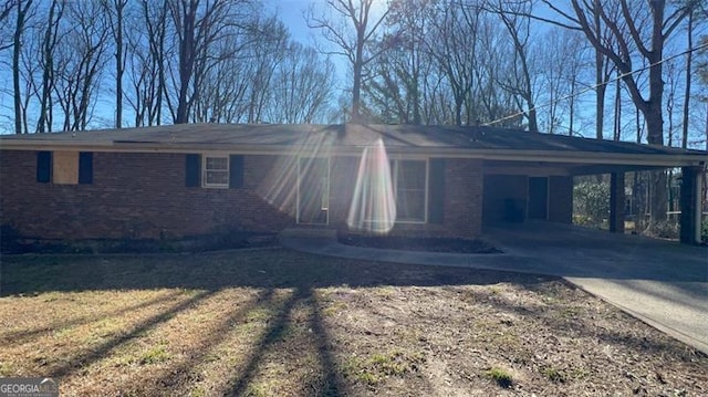 view of side of property with a carport, brick siding, and driveway