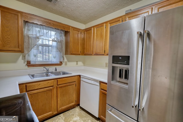 kitchen with a textured ceiling, a sink, light countertops, stainless steel fridge with ice dispenser, and dishwasher