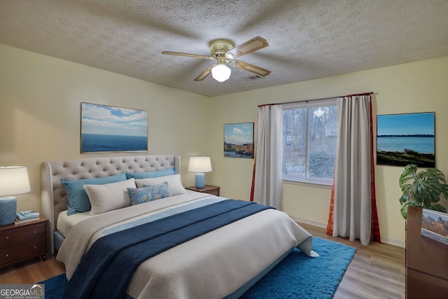 bedroom featuring light wood-style floors, ceiling fan, and a textured ceiling