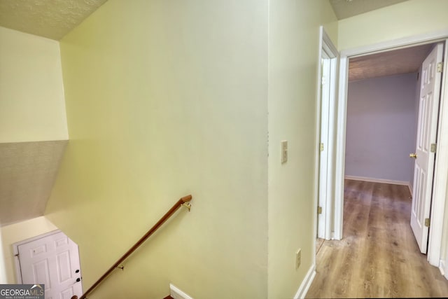 hallway featuring light wood-type flooring, baseboards, and an upstairs landing