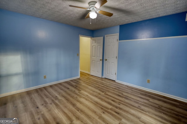 unfurnished bedroom featuring a closet, a ceiling fan, a textured ceiling, wood finished floors, and baseboards