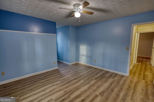 unfurnished bedroom featuring ceiling fan, a textured ceiling, baseboards, and wood finished floors